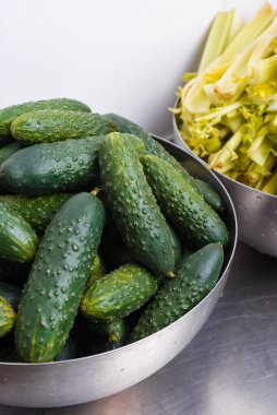 Yeni yıkanmış salatalık ve kereviz dolu iki kâsenin dikey fotoğrafı