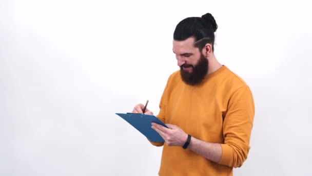 Footage of young bearded man making notes on paper — Stock Video