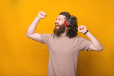 Kulaklıkla müzik dinleyen neşeli, yakışıklı, sakallı bir adamın portresi..