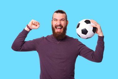 Sakallı heyecanlı bir adamın fotoğrafı elinde bir futbol topuyla çığlık atıyor. .