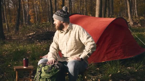 Záběry vousatého hipsterského muže sedícího na židli v lese během západu slunce — Stock video