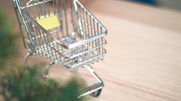 Filmación de un pequeño carrito de compras en un escritorio de madera — Vídeo de stock