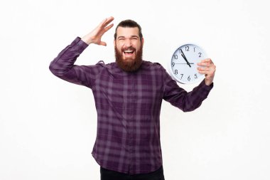 Hüsrana uğramış bir adamın duvar saati tutup el kol hareketi yaptığı fotoğraf..