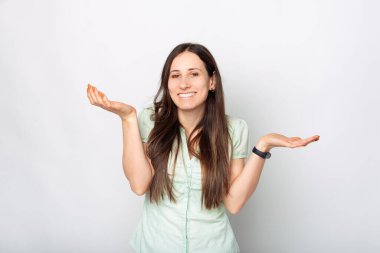 Gülümseyen genç bir kadın beyaz arka planda jestler yaptığını bilmiyor..