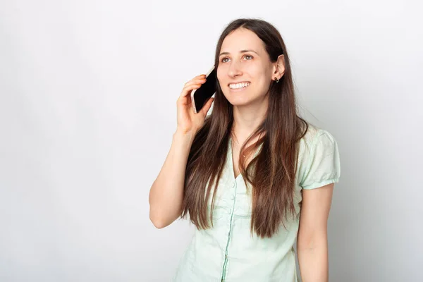 Foto Jovem Mulher Encantadora Sorrindo Falando Telefone Perto Fundo Branco — Fotografia de Stock