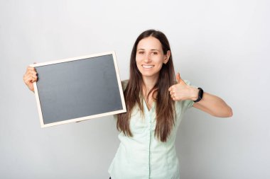 Elinde tahtayla kameraya bakan bir kadının güzel bir fotoğrafı başparmağını kaldırıyor. .