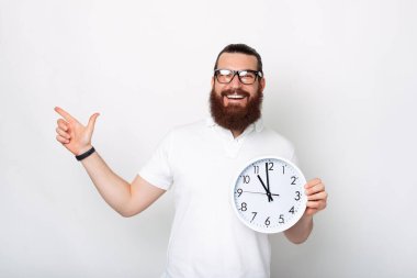 Sakallı neşeli genç adam, gülümsüyor, duvar nöbetini tutuyor ve işaret ediyor..