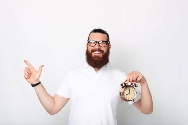 Gülümseyen, sakallı, sakallı ve saati tutan adamın fotoğrafı..