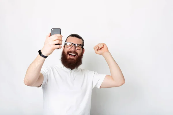 Foto Hombre Barbudo Aspecto Casual Asombrado Con Teléfono Inteligente Celebrando — Foto de Stock