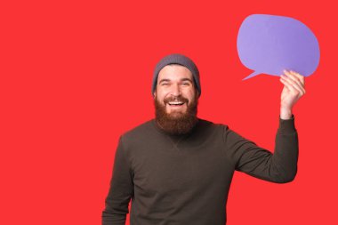 Neşeli genç hippi sakallı adam gülümsüyor ve elinde boş bir konuşma balonu tutuyor..