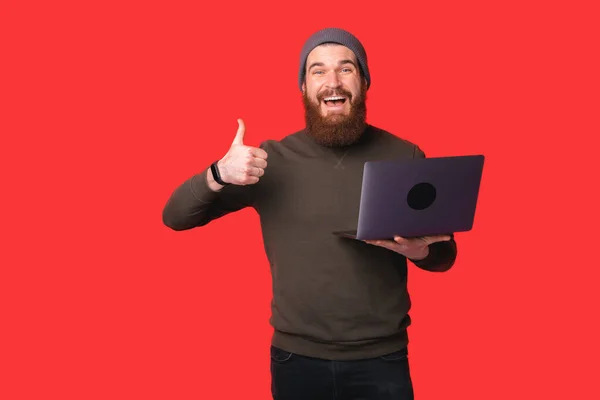 Verblüffter Bärtiger Hipster Mann Zeigt Daumen Hoch Und Hält Laptop — Stockfoto