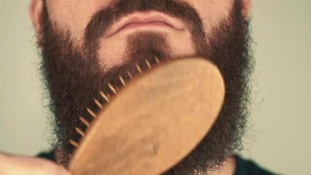 Gros plan de l'homme utilisant un peigne en bois sur sa barbe — Video