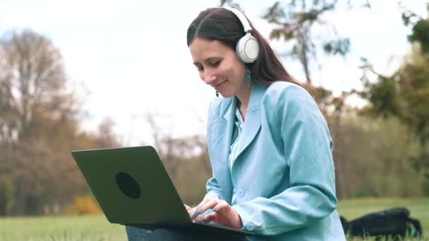 Bilder på glad ung kvinna i casual använder laptop utomhus — Stockvideo