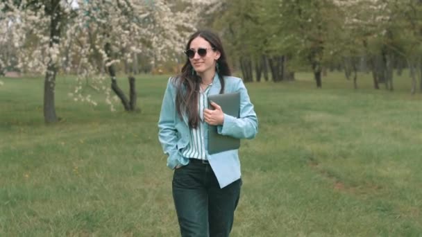 Fotografier av kvinna i tillfällig innehav laptop och promenader i parken — Stockvideo