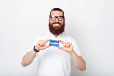 Gülümseyen sakallı adamın portresi mavi kredi kartını gösteriyor..