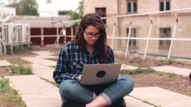 屋外に座ってラップトップを使用している若い女性の映像 — ストック動画