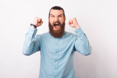 Sıradan mavi gömlekli yakışıklı sakallı adam bağırıyor ve kutluyor..