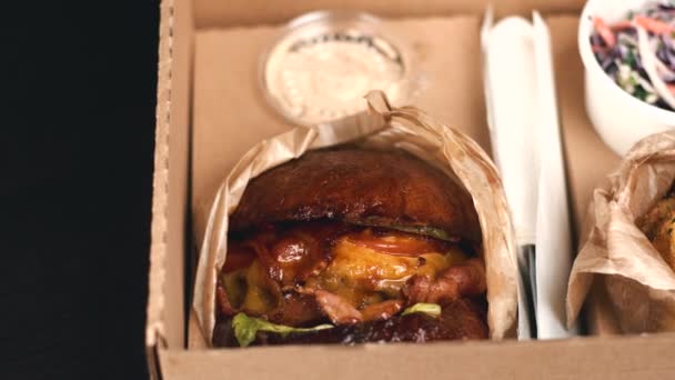 Panning footage of tasty menu of big burger with bacon, potatoes and salad — Stock Video