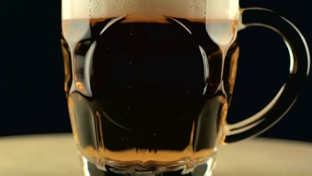 Video panorámico de vaso lleno de cerveza con espuma sobre fondo oscuro — Vídeos de Stock