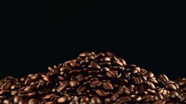 Close up footage over dark background with rotating coffee beans