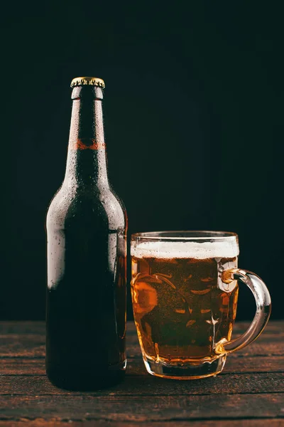 Foto vertical de vaso de cerveza y botella sobre fondo oscuro — Foto de Stock