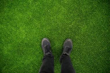 Stadyumdaki yeşil çimlerin üzerinde insan ayağı resmi..