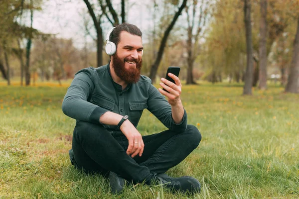 Happy Bearded Hipster Man Sitting Grass Park Listening Music Using — Stock Photo, Image