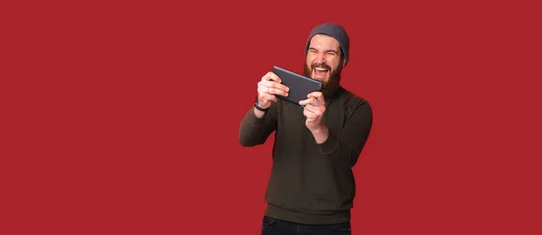 Foto Homem Hipster Barbudo Feliz Jogando Jogos Tablet Sobre Fundo — Fotografia de Stock