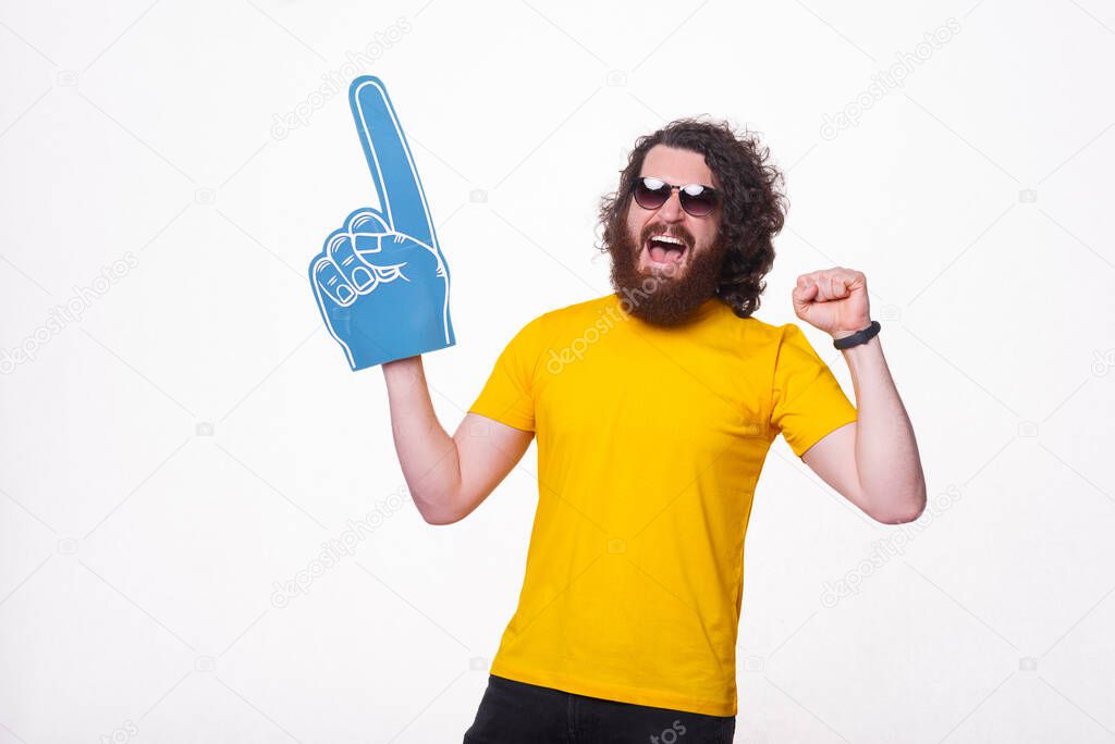 Amazed man with beard screaming and supporting his favorite sport team and pointing with fun glove.