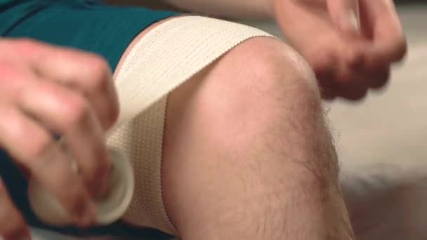 Primo piano filmato di uomo che fa benda sul ginocchio — Video Stock
