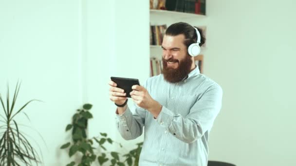 Footage of bearded office man playing games at tablet during free time — Stock Video