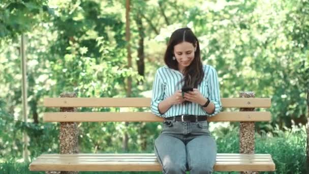 Video av ung kvinna som sitter på stol och skriva på smartphone — Stockvideo