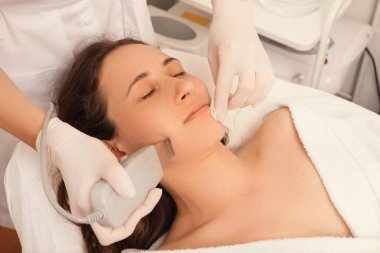 Genç bir kadının yüz derisi üzerinde ultrasonik tedavisiyle ilgili fotoğraf..