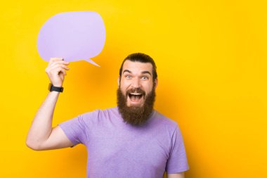 Heyecanlı sakallı adam konuşma baloncuğu tutuyor sarı arkaplan üzerine yazı yazmak için boş alanı var