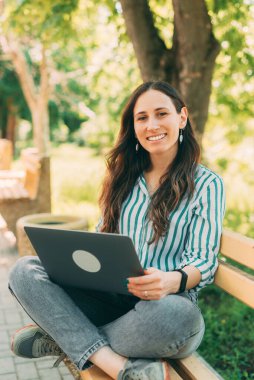 Banktaki kız dizüstü bilgisayar kullanıyor, uzaktan çalışan serbest çalışan.