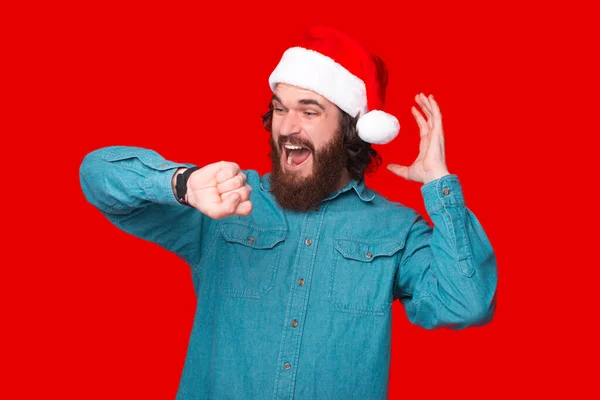 Photo Amazed Bearded Man Santa Claus Hat Looking Watch — Stock Photo, Image