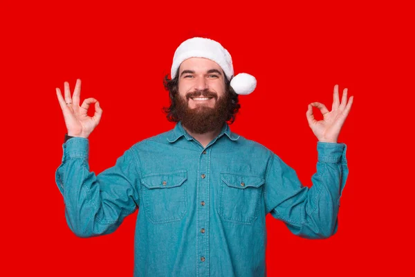 Photo Cheerful Bearded Man Wearing Santa Claus Hat Making Zen — Zdjęcie stockowe