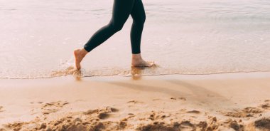 Gün batımında sahilde koşan kadın bacaklarının fotoğrafını çek..