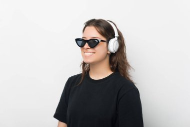 Pozitif bir genç kızın güneş gözlüğü takıp müzik dinlerken çekilmiş güzel bir portresi. .