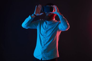 Sakallı adam neon ışıklar arasında sanal gerçeklik deneyimi yaşıyor. Sanal gerçeklik gözlüğü kullanan kişi. boş zaman ve modern teknoloji