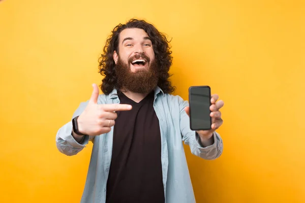 Joyeux Jeune Homme Hipster Barbu Pointant Vers Smartphone Sur Fond — Photo