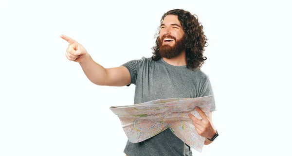 Zdjęcie Uśmiechniętego Brodatego Podróżnika Trzymającego Mapę Wskazującego Drogę — Zdjęcie stockowe