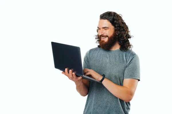 Fröhlicher Junger Mann Mit Bart Lächelt Und Benutzt Laptop Auf — Stockfoto