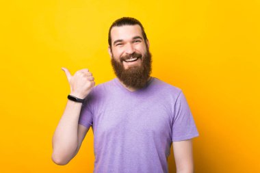 Sarı arka planı işaret eden gülümseyen sakallı bir adamın portresi..