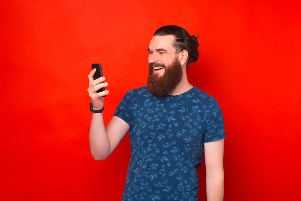 Handsome Bearded Smiling Man Looking Phone Talking Someone Red Background — Stock Photo, Image