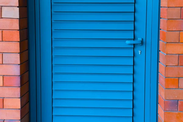 Puerta de madera pintada azul en una pared de ladrillo rojo. — Foto de Stock