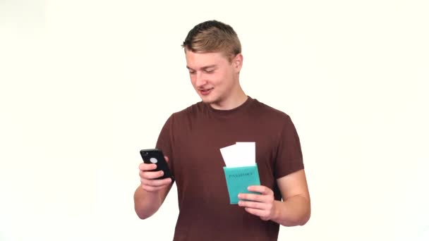 Видеозапись молодого человека, использующего смартфон и держащего паспорт с билетами на самолет — стоковое видео