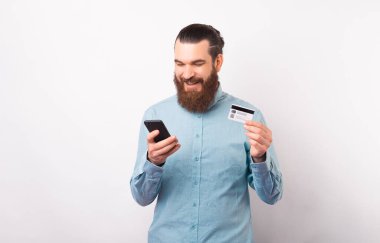 Gülümseyen adam elinde kart tutarken internet ya da cep telefonu bankacılığı kullanıyor.