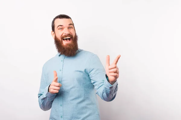 Sie rocken. Bärtiger Mann gestikuliert und zeigt auf weißen Hintergrund. — Stockfoto