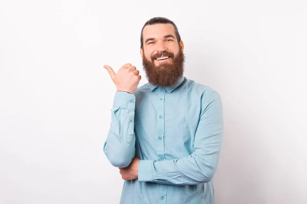 Amplio hombre sonriente señala a un lado con su pulgar. —  Fotos de Stock